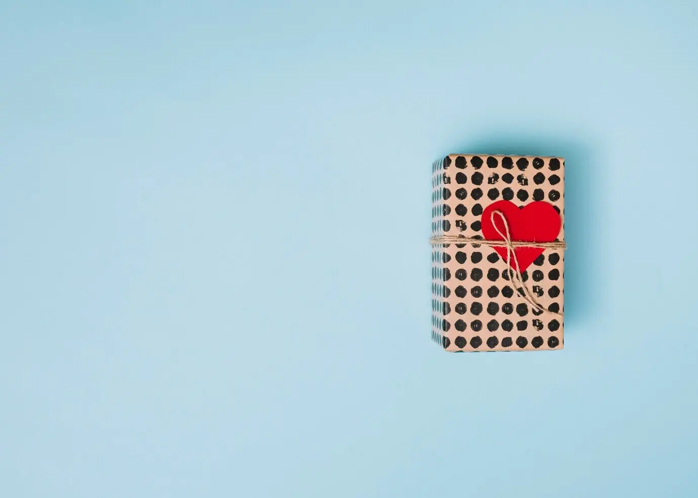 Geschenk in Bonbonpapier mit dekorativem Herz und gedrehtem Ende.